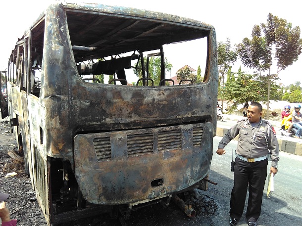 Petugas kepolisian meninjau bus yang terbakar di Jalan Pramuka Bandar Lampung, Minggu 6//12/2015. | Andi/Jejamo.com