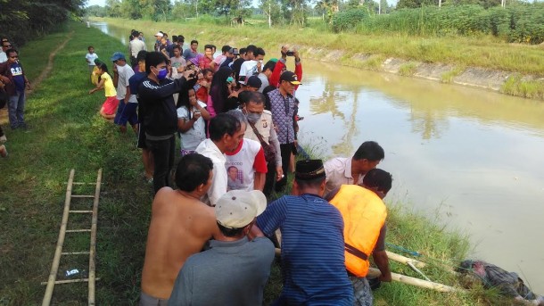 Warga berusaha mengangkat mayat Mahmud yang ditemukan tewas di saluran irigasi Kampung Karang Endah Lampung Tengah, Sabtu, 16/7/2016. | Raeza Handani/Jejamo.com 