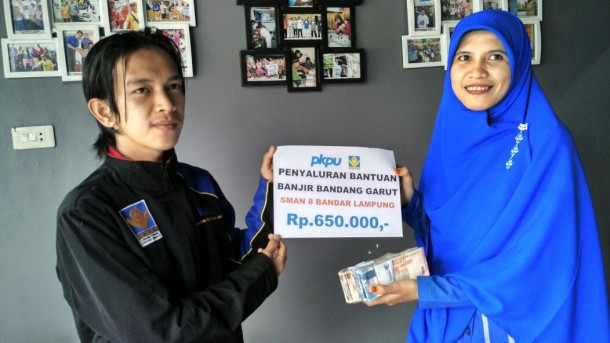 Faisal Anwar dari FKAR Bandar Lampung menyerahkan uang hasil penggalangan dana korban banjir Garut kepada Anggun Erpiyana dari PKPU Lampung. | Ist 